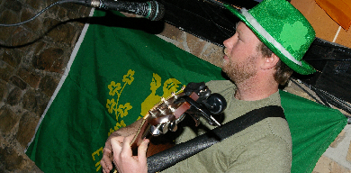 man playing guitar with green hat on